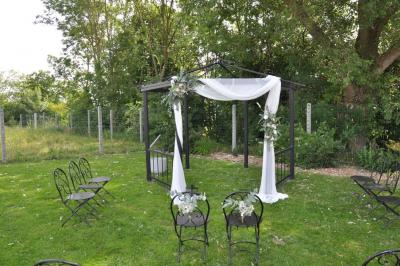 Salle de réception en briques avec tables rondes dressées, nappes blanches et décoration de mariage.
