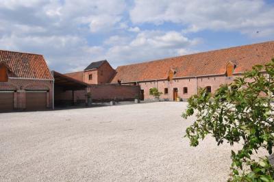 Salle de réception en briques avec tables rondes dressées, nappes blanches et décoration de mariage.