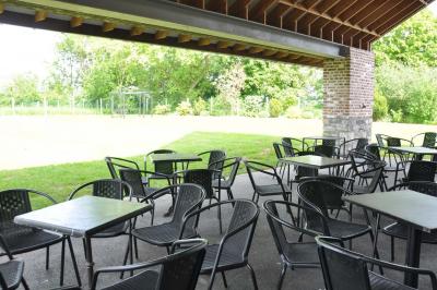 Salle de réception en briques avec tables rondes dressées, nappes blanches et décoration de mariage.