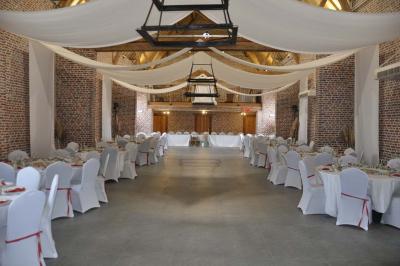 Salle de réception en briques avec tables rondes dressées, nappes blanches et décoration de mariage.