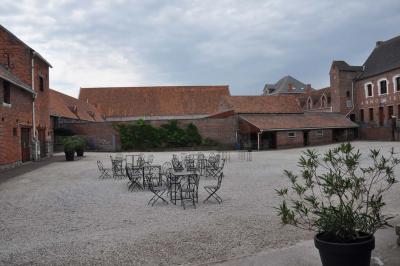 Salle de réception en briques avec tables rondes dressées, nappes blanches et décoration de mariage.