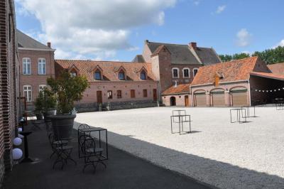 Salle de réception en briques avec tables rondes dressées, nappes blanches et décoration de mariage.