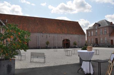 Salle de réception en briques avec tables rondes dressées, nappes blanches et décoration de mariage.