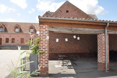 Salle de réception en briques avec tables rondes dressées, nappes blanches et décoration de mariage.
