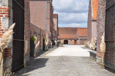 Salle de réception en briques avec tables rondes dressées, nappes blanches et décoration de mariage.