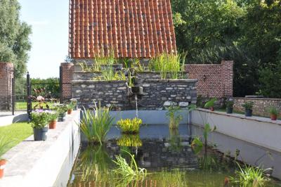 Salle de réception en briques avec tables rondes dressées, nappes blanches et décoration de mariage.