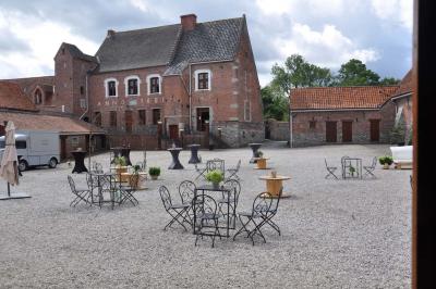 Salle de réception en briques avec tables rondes dressées, nappes blanches et décoration de mariage.
