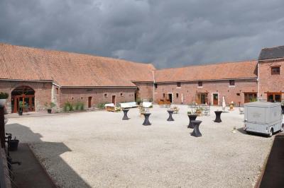 Salle de réception en briques avec tables rondes dressées, nappes blanches et décoration de mariage.