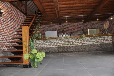 Salle de réception en briques avec tables rondes dressées, nappes blanches et décoration de mariage.