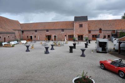 Salle de réception en briques avec tables rondes dressées, nappes blanches et décoration de mariage.