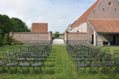 Salle de réception en briques avec tables rondes dressées, nappes blanches et décoration de mariage.