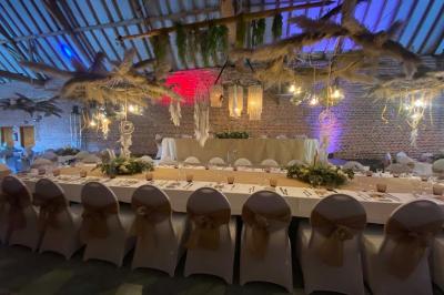 Salle de réception en briques avec tables rondes dressées, nappes blanches et décoration de mariage.