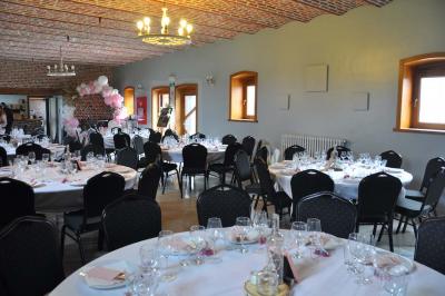 Salle de réception en briques avec tables rondes dressées, nappes blanches et décoration de mariage.