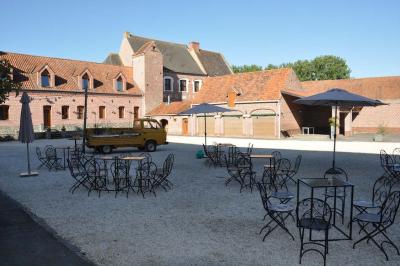 Salle de réception en briques avec tables rondes dressées, nappes blanches et décoration de mariage.