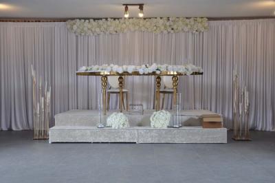 Salle de réception en briques avec tables rondes dressées, nappes blanches et décoration de mariage.