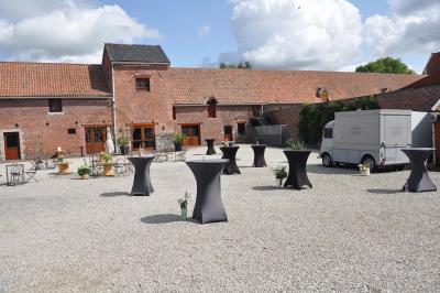 Salle de réception en briques avec tables rondes dressées, nappes blanches et décoration de mariage.