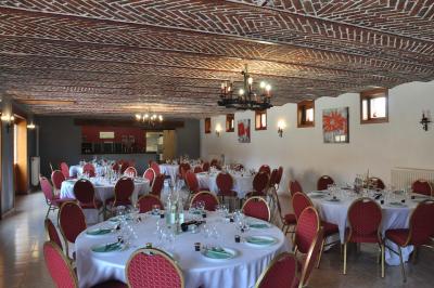 Salle de réception en briques avec tables rondes dressées, nappes blanches et décoration de mariage.