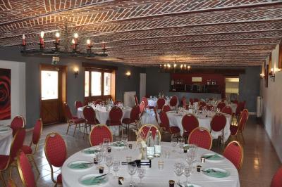 Salle de réception en briques avec tables rondes dressées, nappes blanches et décoration de mariage.
