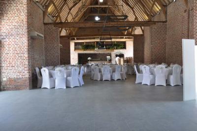 Salle de réception en briques avec tables rondes dressées, nappes blanches et décoration de mariage.