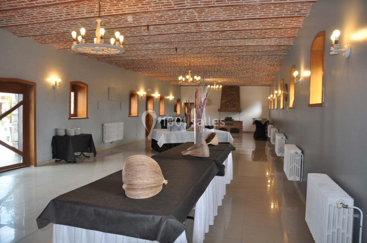 Salle de réception avec plafond en briques, tables recouvertes de nappes noires et décorations en osier.