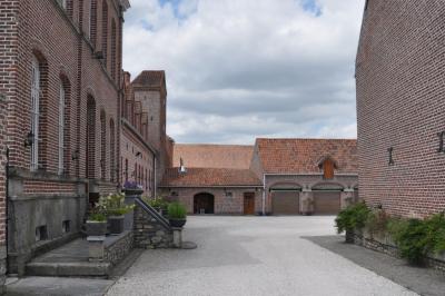 Salle de réception en briques avec tables rondes dressées, nappes blanches et décoration de mariage.