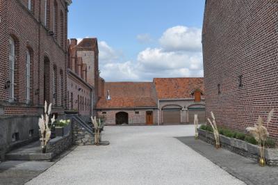 Salle de réception en briques avec tables rondes dressées, nappes blanches et décoration de mariage.