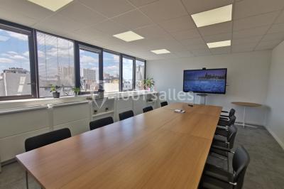Table garnie de petits fours, desserts et plantes décoratives dans une salle lumineuse avec murs blancs.