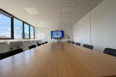 Table garnie de petits fours, desserts et plantes décoratives dans une salle lumineuse avec murs blancs.