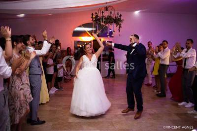 Allée bordée de cyprès et de vignes avec une vue sur une montagne en arrière-plan, sous un ciel clair.