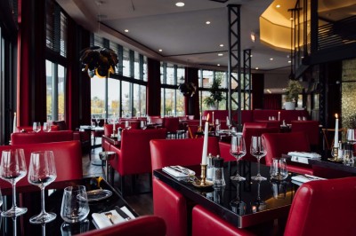 Robe de mariée, bouquet de fleurs, chaussures et bijoux posés près d'une table sur tapis rouge.