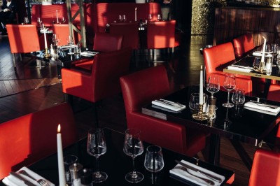 Robe de mariée, bouquet de fleurs, chaussures et bijoux posés près d'une table sur tapis rouge.