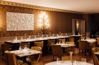 Robe de mariée, bouquet de fleurs, chaussures et bijoux posés près d'une table sur tapis rouge.