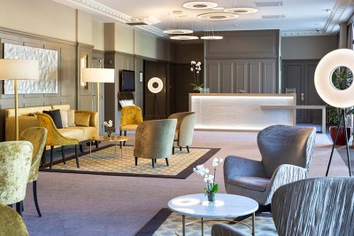 Robe de mariée, bouquet de fleurs, chaussures et bijoux posés près d'une table sur tapis rouge.