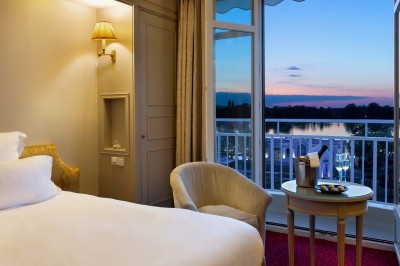 Robe de mariée, bouquet de fleurs, chaussures et bijoux posés près d'une table sur tapis rouge.