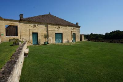 Vue aérienne d'un domaine entouré de vignes, de bâtiments en pierre et d'un cours d'eau bordé de verdure.