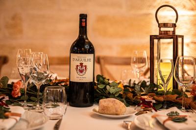Vue aérienne d'un domaine entouré de vignes, de bâtiments en pierre et d'un cours d'eau bordé de verdure.