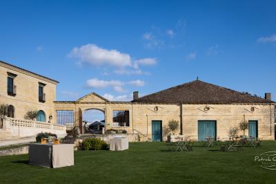 Vue aérienne d'un domaine entouré de vignes, de bâtiments en pierre et d'un cours d'eau bordé de verdure.