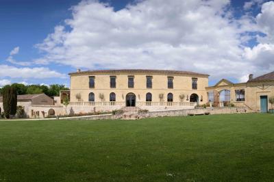 Vue aérienne d'un domaine entouré de vignes, de bâtiments en pierre et d'un cours d'eau bordé de verdure.