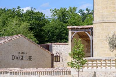Vue aérienne d'un domaine entouré de vignes, de bâtiments en pierre et d'un cours d'eau bordé de verdure.
