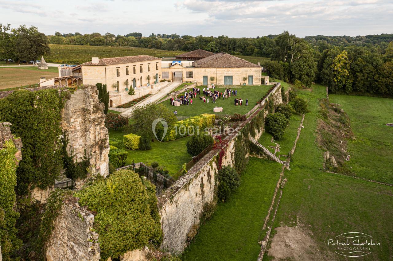 Vue aérienne d'un domaine avec des bâtiments en pierre, des ruines anciennes et un jardin accueillant un rassemblement de…