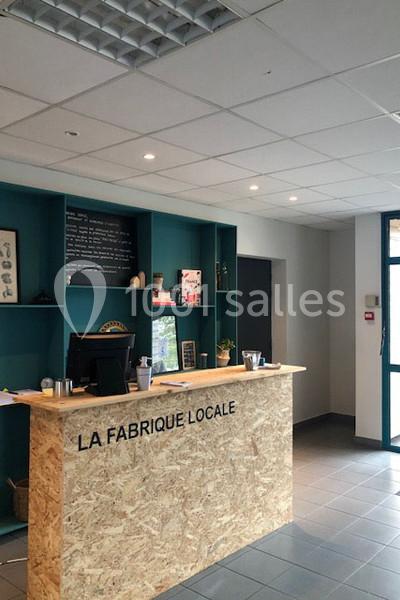 Comptoir en bois devant une étagère murale turquoise dans un espace lumineux avec plafond à dalles blanches.