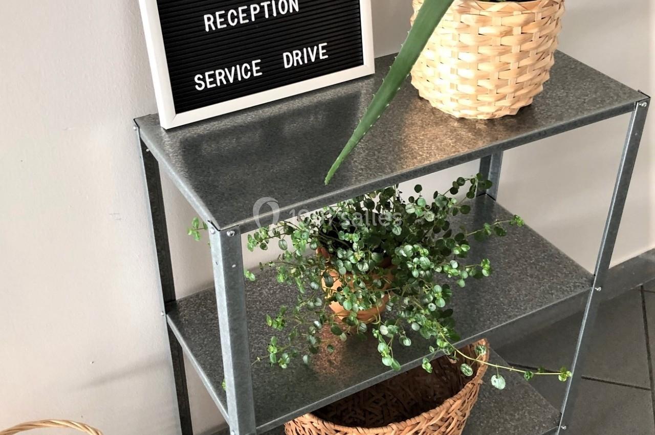 Étagère métallique avec plantes en pots tressés et panneau indiquant un restaurant et service drive.