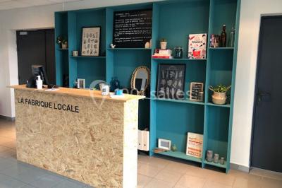 Pelouse verdoyante avec un grand arbre, bâtiment moderne en arrière-plan et ciel dégagé.