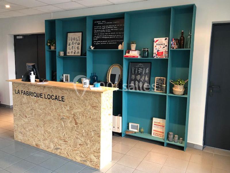Comptoir en bois devant une étagère murale turquoise contenant des objets décoratifs et des livres, dans un espace intérieur.