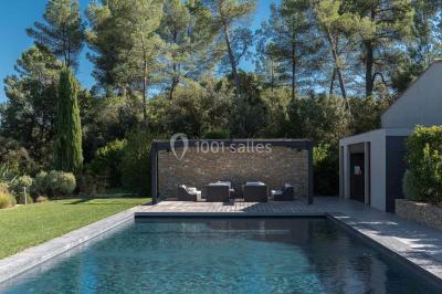 Bâtiment moderne entouré de végétation, avec un chemin pavé et des panneaux indiquant des salles et des logements.