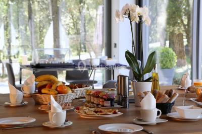 Bâtiment moderne entouré de végétation, avec un chemin pavé et des panneaux indiquant des salles et des logements.