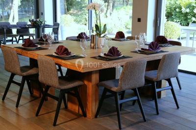 Bâtiment moderne entouré de végétation, avec un chemin pavé et des panneaux indiquant des salles et des logements.