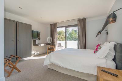 Bâtiment moderne entouré de végétation, avec un chemin pavé et des panneaux indiquant des salles et des logements.