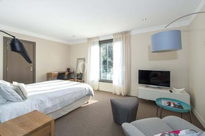 Bâtiment moderne entouré de végétation, avec un chemin pavé et des panneaux indiquant des salles et des logements.