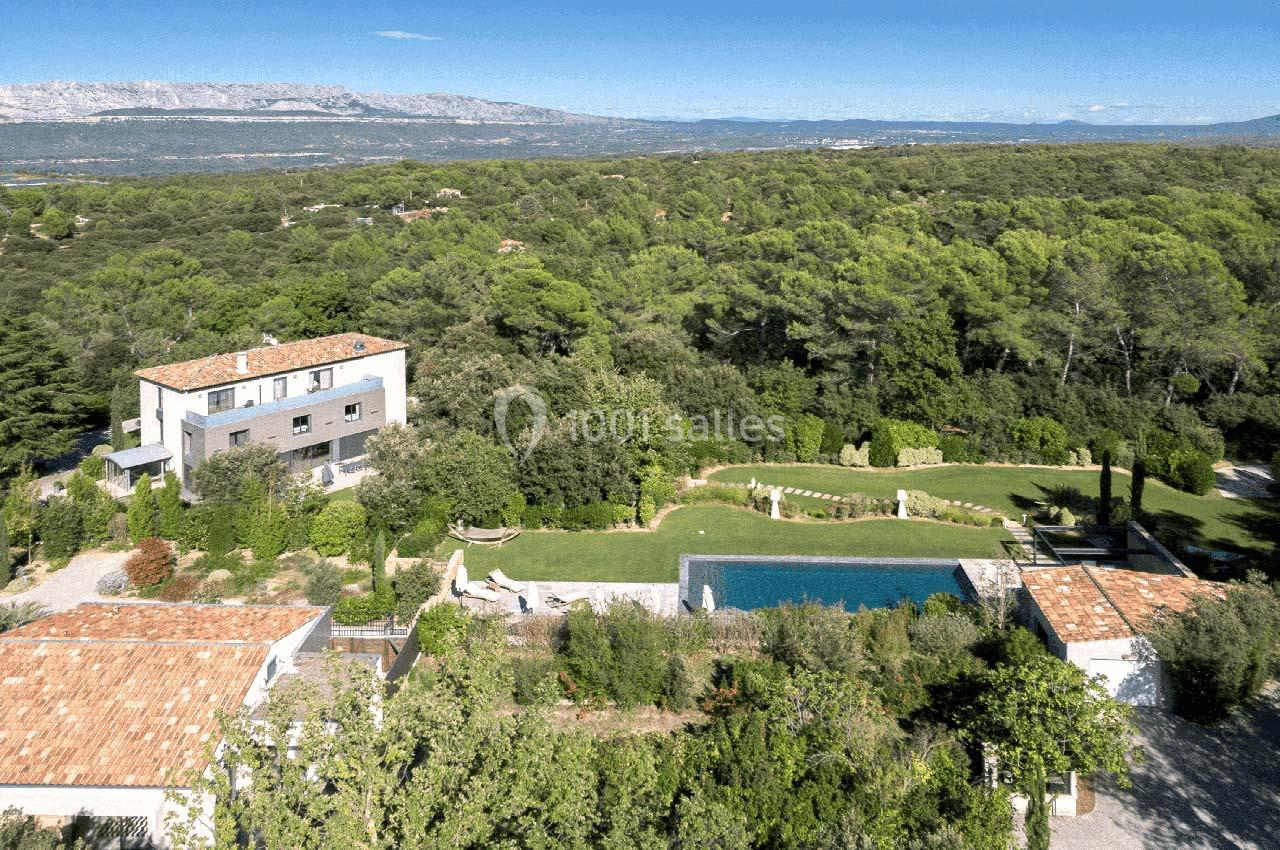 Vue aérienne d'une propriété avec piscine, entourée de végétation et de bâtiments aux toits en tuiles.